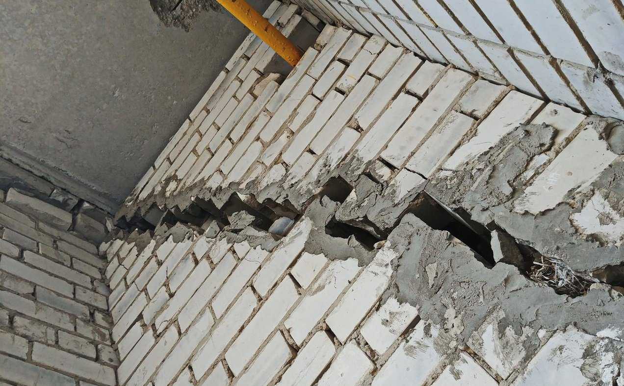 Сквозная трещина в стене. Трещина в многоэтажном доме. Разрушение строительных конструкций. Дефекты кирпичной кладки. Трещина в несущей стене.